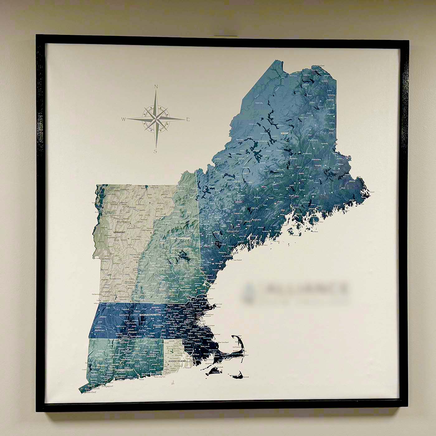 Blue and Gray New_England_Detailed_Map with black frame on cream colored wall.